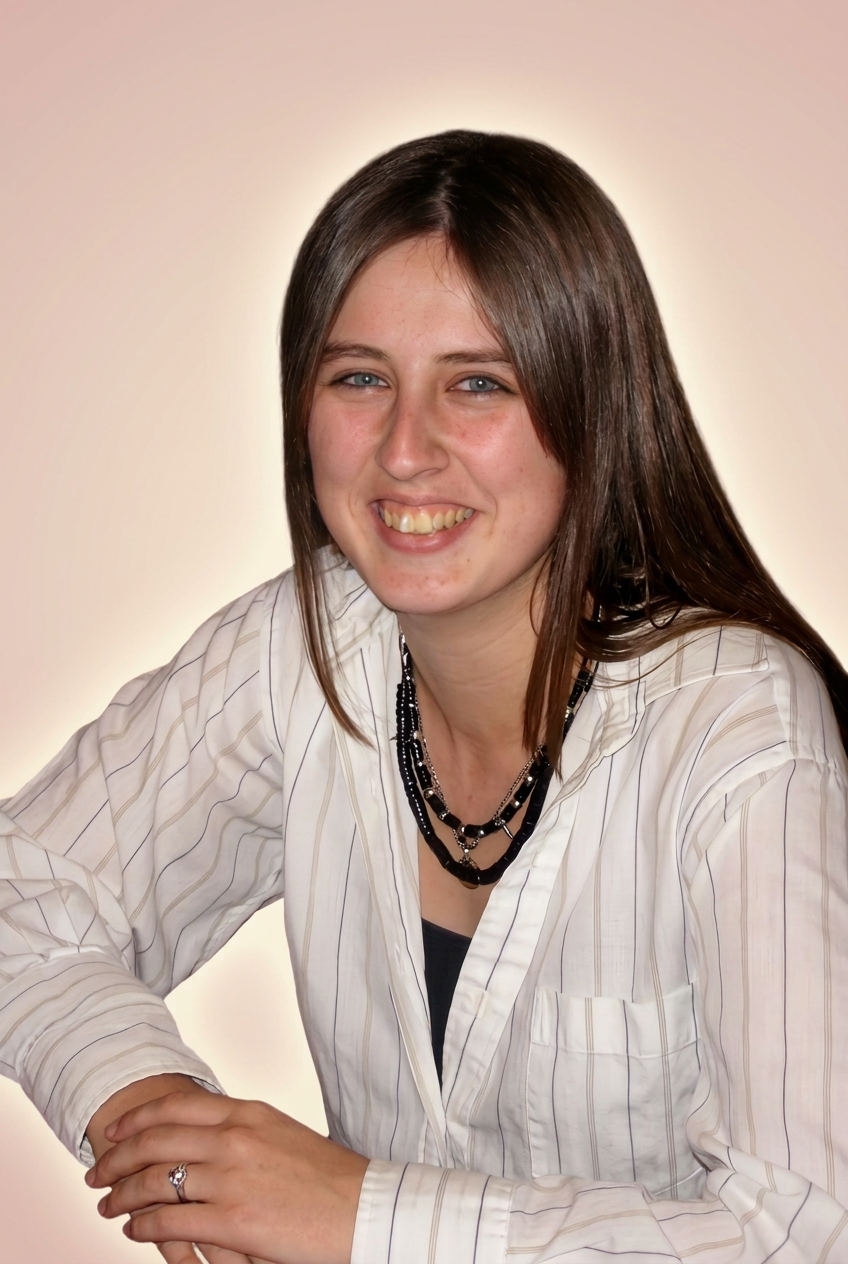 Tanya, a young woman with long brown hair, smiling softly in a white shirt